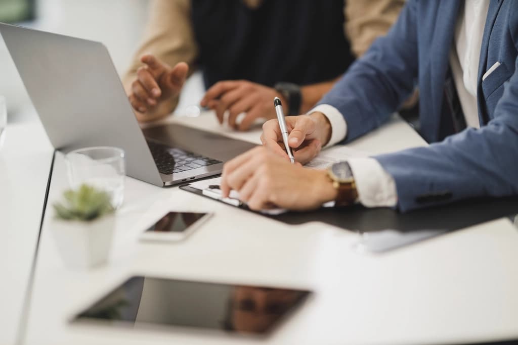 Professionals reviewing documents at a desk with laptops